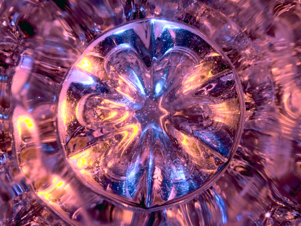 The chakras answer to light, color, and sound — frequency speaking to frequency. Light refracting into violet and gold through a crystal
